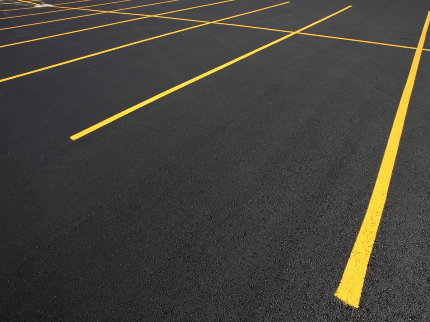 New yellow parking lot lines painted on fresh dark asphalt